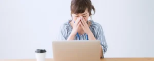 パソコンの前でめまいをしている女性